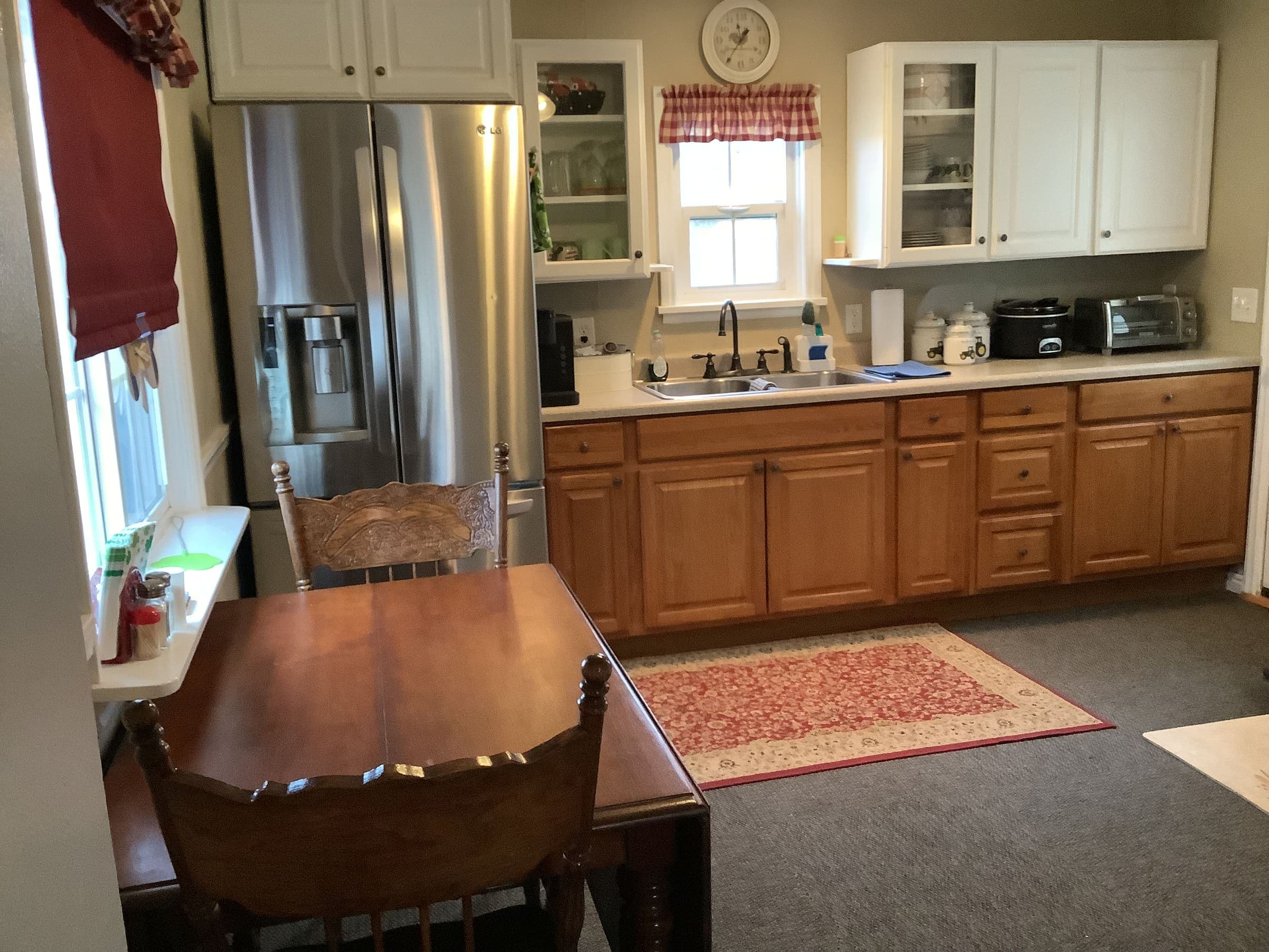 Farmhouse kitchen with a full-size refrigerator, wood cabinets, and a dining table with area rug