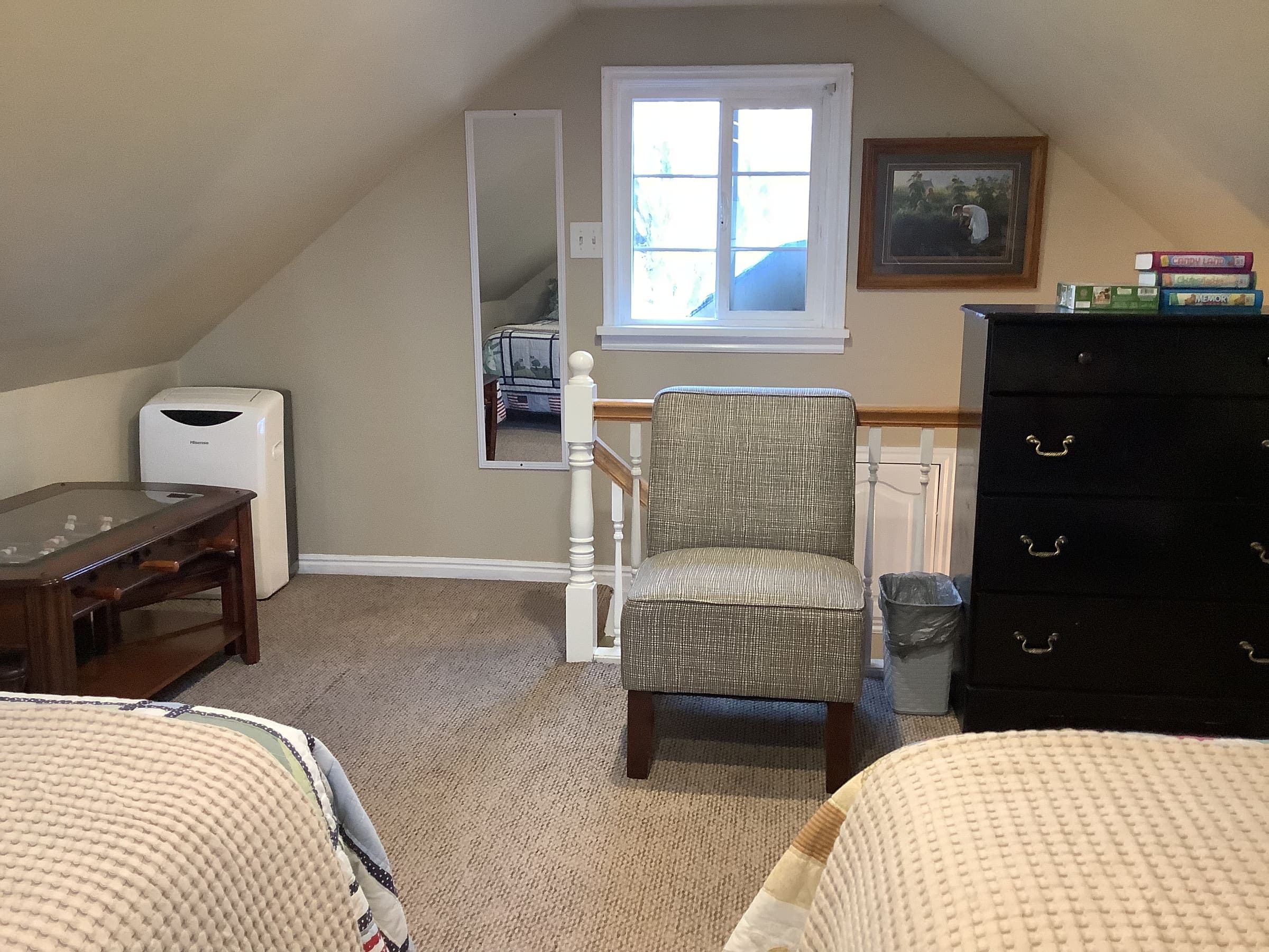 Loft sitting area with an armchair, dresser, and foosball table, next to the foot of the loft beds