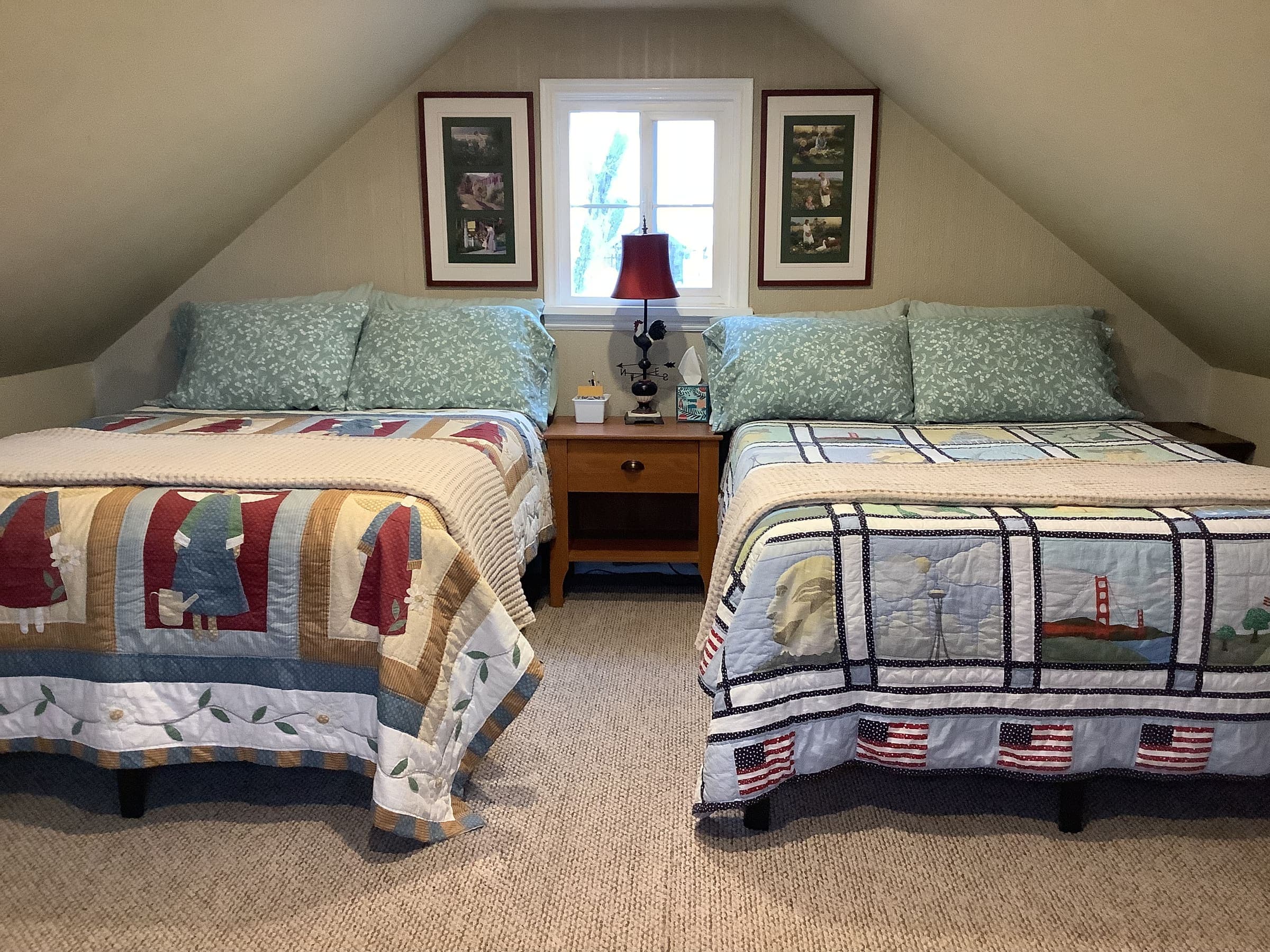 Two full-size beds with patchwork quilts in the upstairs loft, tucked under the sloped farmhouse ceiling